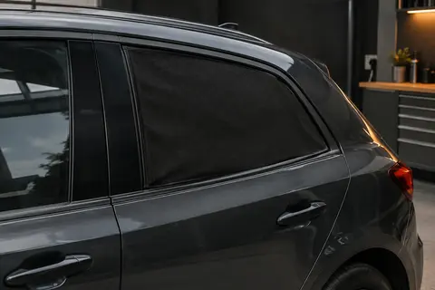 Deux pare-soleils noirs en maille installés sur les vitres arrière d’une voiture anthracite