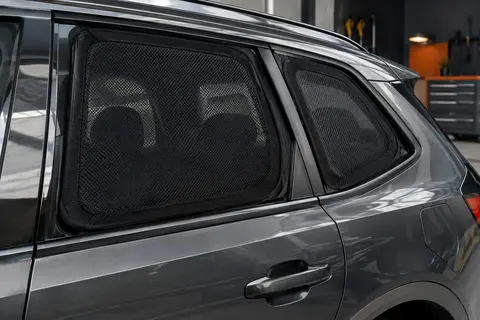 Deux pare-soleils chaussettes en maille noire posés sur les vitres arrière d’une voiture anthracite