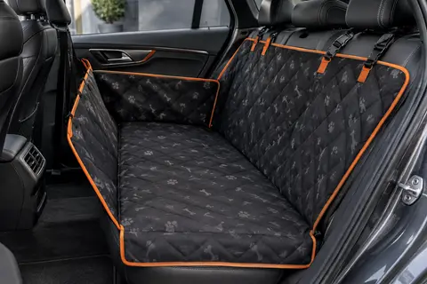 Housse de siège auto noire et orange avec motif de pattes, installée sur une banquette arrière