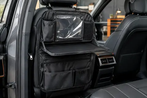 Organiseur noir fixé au dossier d’un siège auto, avec poches, poche transparente et plateau pliant
