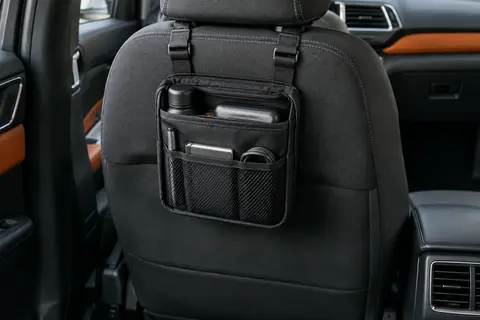 Organisateur auto noir suspendu à un dossier anthracite, avec poches, sangles réglables et petits objets rangés